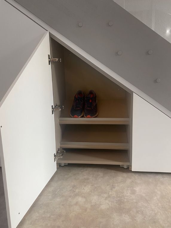 Geöffnete Schuhschranktüre unter der Treppe