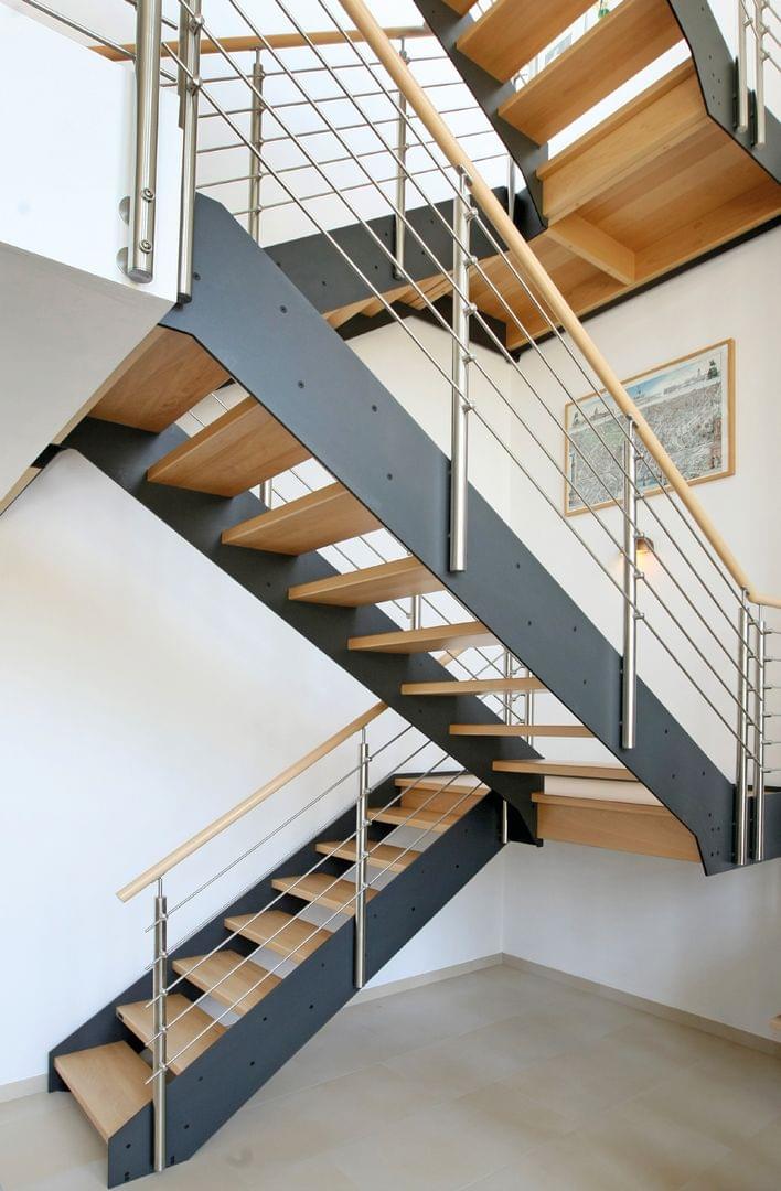 Holztreppe Loft halbgewendelte Schmalwangentreppe mit Edelstahl Reling und Podest im Treppenhaus